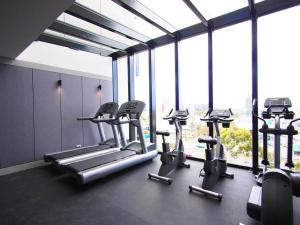 a gym with several cardio machines in a room with windows at 1 Bedroom Modern Apartment Near Crown and CBD in Melbourne