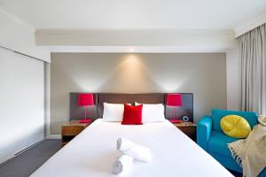 a bedroom with a large white bed and a blue chair at King Studio Harbourfront Haven with Tropical Pool in Darwin