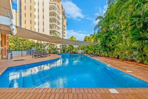 una piscina con sedie e un edificio di King Studio Harbourfront Haven with Tropical Pool a Darwin