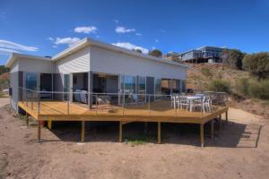 a house with a large deck with a table and chairs at Sandbar Beach House in Coles Bay