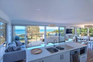 a kitchen and living room with a view of the ocean at Sandbar Beach House in Coles Bay