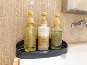 three bottles of soap sitting on a holder on a bathroom sink at Tabist Hotel Please Kobe in Kobe