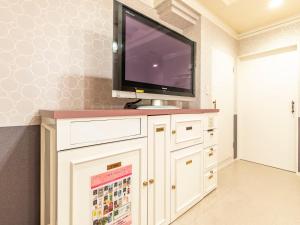 a tv on top of a white cabinet in a room at Tabist Hotel Please Kobe in Kobe