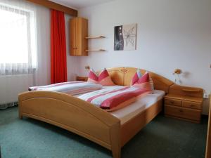 una camera da letto con un grande letto con cuscini rosa di Ferienwohnungen Schnarf a Valdaora