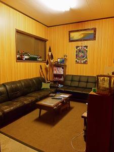 a living room with a leather couch and a coffee table at Aoshima Guesthouse Hooju in Miyazaki