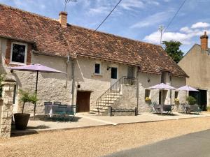 a building with purple umbrellas and tables and chairs at Les gîtes de Joséphine in Courbouzon