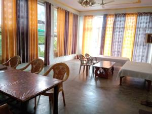 sala de estar con mesas, sillas y ventanas en KIRAN GUEST HOUSE en Bharatpur