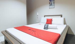 a bed with red and white sheets and a red pillow at RedDoorz @ Bridgeway Hotel Tuguegarao City in Tuguegarao City