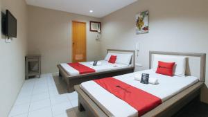 2 camas en una habitación de hotel con almohadas rojas y blancas en RedDoorz @ Bridgeway Hotel Tuguegarao City, en Tuguegarao