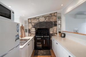 a kitchen with a stove and a stone wall at Magnetic Cottage circa 1850s in Port Fairy