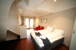um quarto com uma cama branca e uma cadeira vermelha em Villa Oleanna em Lysekloster