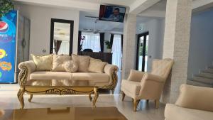 uma sala de estar com um sofá e duas cadeiras em Pensiunea GOLD Wellness&Spa em Chişcău
