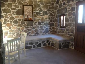 a stone wall with a bench in a room at Loutra Olive Garden Stone House #3 in Mandrakion