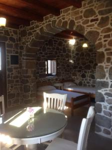 a table and chairs in a room with a stone wall at Loutra Olive Garden Stone House #3 in Mandrakion
