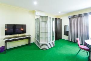 a room with a green floor and a table and chair at RedDoorz at Brother Homestay Kupang in Kupang