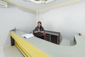 una mujer parada en una habitación vacía con un mostrador en RedDoorz at Brother Homestay Kupang en Kupang
