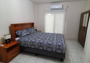 um quarto com uma cama com um edredão azul e branco em Andy's House em San Cristóbal