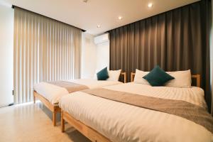 2 łóżka w pokoju hotelowym z oknami w obiekcie TAKETO STAY Sumikawa House w mieście Sapporo