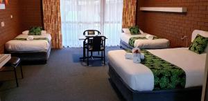 a room with four beds and a table and chairs at Barooga Country Inn Motel in Barooga