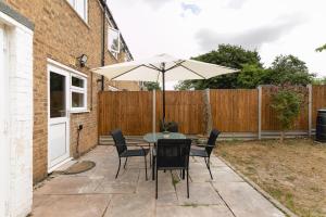 um pátio com uma mesa, cadeiras e um guarda-sol em Skyvillion - STEVENAGE SPACIOUS COMFY 2BED HOUSE with Garden, Free WiFi & Parking em Shephall