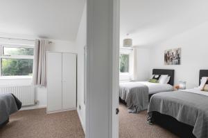 a white bedroom with two beds and a window at Skyvillion - STEVENAGE SPACIOUS COMFY 2BED HOUSE with Garden, Free WiFi & Parking in Shephall