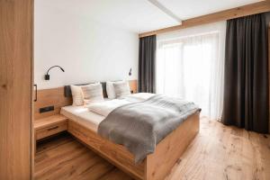 1 dormitorio con 1 cama grande en una habitación con ventana en Hohe Tauern Lofts Panoramabahn by Alpina-Holiday, en Dorf
