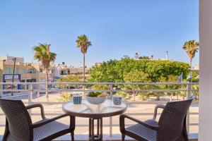 a table and chairs on a balcony with palm trees at Bella Apartment in Kissamos