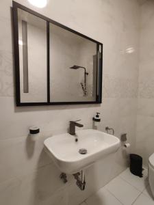 Baño blanco con lavabo y espejo en Qawra Apartment, en St Paul's Bay