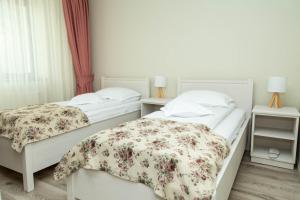 two beds in a hotel room with flowers at Pensiunea Casablanca in Reghin