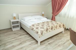 a bedroom with a white bed with a floral bedspread at Pensiunea Casablanca in Reghin