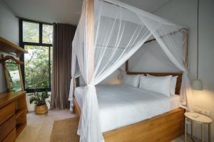 a bedroom with a white bed with a canopy at Villa Utamaro in Bumbang