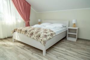 a bedroom with a white bed with a floral bedspread at Pensiunea Casablanca in Reghin