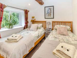 two beds in a bedroom with a window at Fox Bank Cottage in Macclesfield