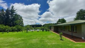 a house with a large yard next to a building at Apple Blossom Cottage in Dullstroom