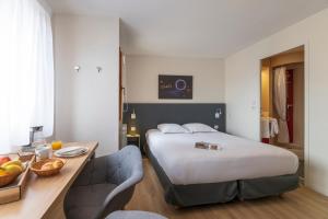 una habitación de hotel con una cama y una mesa con un bol de fruta en Cerise Nantes La Beaujoire, en Nantes