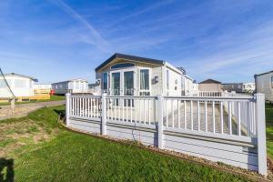 a white fence in front of a house at Beautiful, Pet Friendly Caravan By The Beach In Suffolk Ref 40126nd in Lowestoft