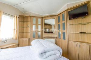 a bedroom with a bed and a tv and wooden cabinets at Beautiful, Pet Friendly Caravan By The Beach In Suffolk Ref 40126nd in Lowestoft