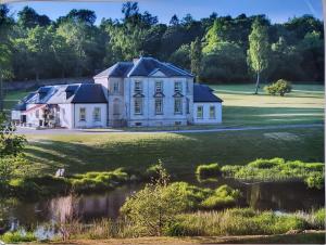 una gran casa blanca en un campo con un estanque en Glassford House, en Glasgow