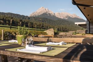 una mesa de madera con servilletas y montañas en el fondo en JOAS natur.hotel.b&b en San Candido