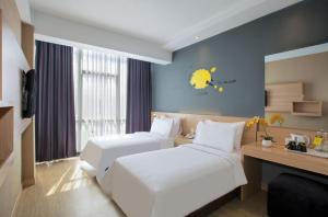 una camera d'albergo con due letti e una scrivania di ROOMS INC d'botanica Bandung a Bandung Altre 39 foto