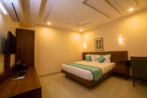 a bedroom with a bed and a desk and a television at The Bliss Hotel in Hubli