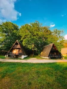 dos cabañas con techo de paja están sentadas en el césped en Leśny Dwór en Janowice Wielkie