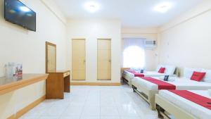 um quarto de hotel com quatro camas e uma televisão em RedDoorz @ Goldland Spring Resort Urdaneta City em Urdaneta