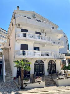 a white building with a palm tree in front of it at Fimi Apartments in Ulcinj