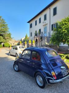 een kleine blauwe auto geparkeerd voor een gebouw bij Cortona Resort & Spa in Cortona
