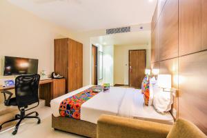 a bedroom with a bed and a desk and a chair at FabHotel RK International in Mumbai