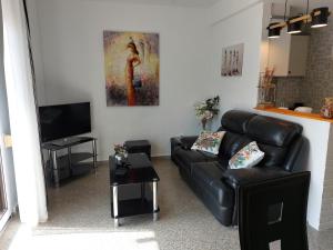 a living room with a black leather couch and a television at Casita Amigo in Moraira
