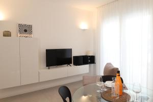 a living room with a table and a tv on a wall at Residence TRE LEONI in Caorle