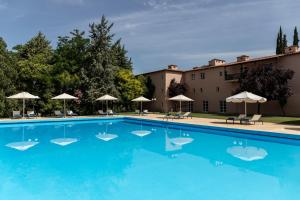 a large blue swimming pool with umbrellas and a building at Amalia Hotel Kalambaka in Kalabaka