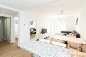 ein weißes Wohnzimmer mit einem Tisch und einem Sofa in der Unterkunft Casablanca 4 Apartamento con jardín privado in Fuengirola